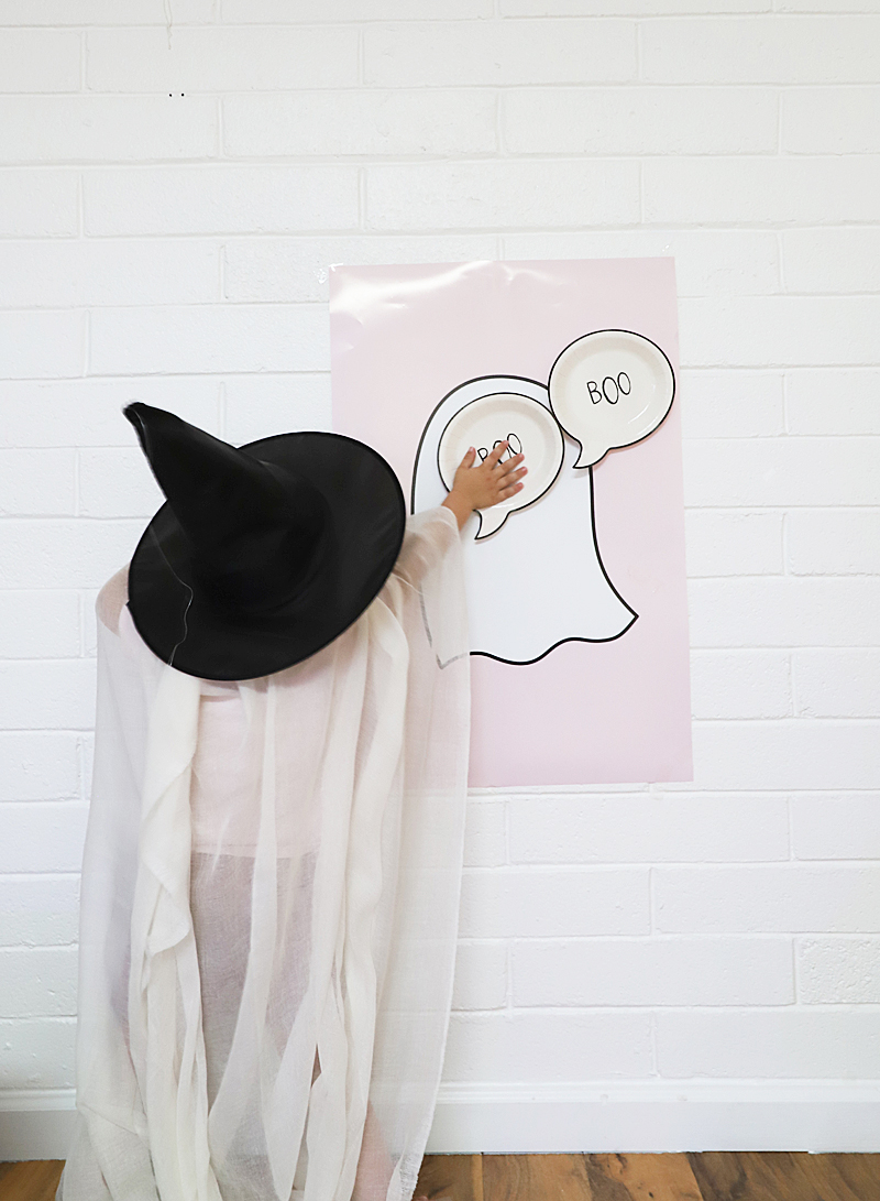 little ghost witch placing a boo on a ghost poster for pin the boo halloween game
